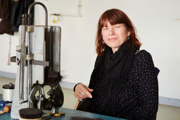 Sehbehinderte Frau sitzt vor Bürstenziehmaschine.